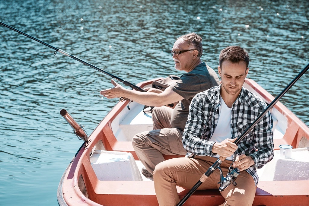 Dois homens sentados em um barco e segurando uma vara de pesca