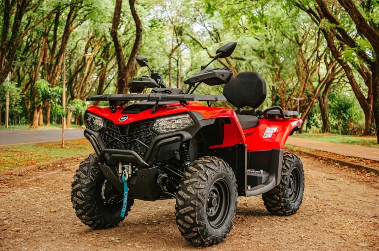 Quadriciclo vermelho parado em estrada de terra arborizada